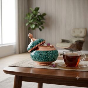 Open turquoise inlay sugar bowl filled with sugar cubes and rosebuds next to steaming black tea.