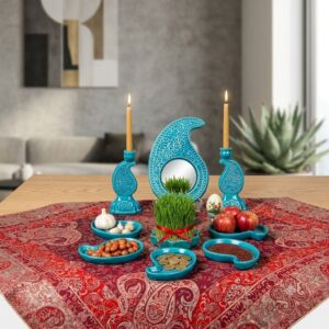 Handcrafted turquoise enamel pottery Haft-sin set on a red Persian woven tablecloth.