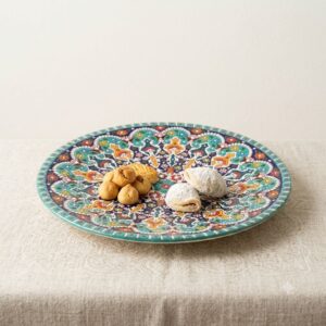 Close-up of handmade round enamel dish with artisan cookies on linen fabric.