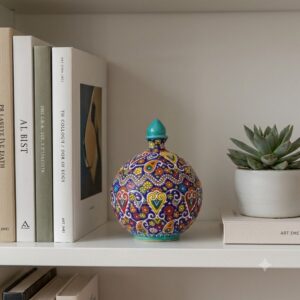 Persian enamel ceramic dish displayed on a white bookshelf next to books and succulent.