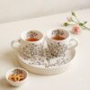 Purple GOLRIZ handcrafted ceramic tea cups on floral tray with small snack bowl.