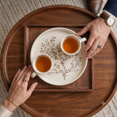 Top-down view of hands holding the Purple GOLRIZ hand-painted ceramic tray and tea cups.