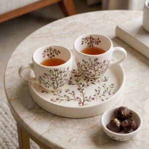 Hand-painted purple botanical ceramic coffee cups on tray with chocolates.