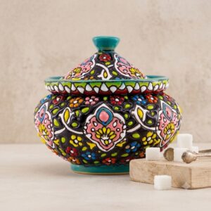 Handmade Hamedan enamel pottery sugar bowl next to sugar cubes and brass tongs.