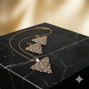 Close-up of a geometric hand-woven bead jewelry set featuring a luxurious gold-and-black palette on a dark marble surface.
