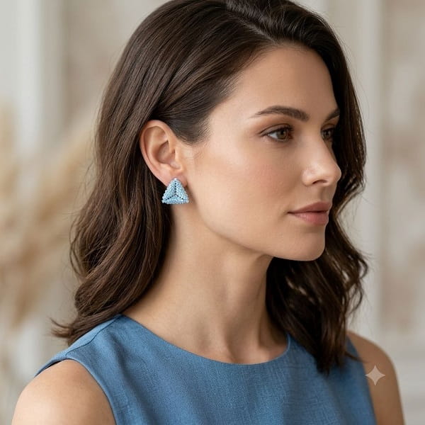 Woman wearing light blue 3D beaded triangle stud earrings in side profile.