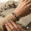 Detailed macro view of the luxurious gold-and-black palette and geometric patterns of the cow print bracelet on a textured stone slab.