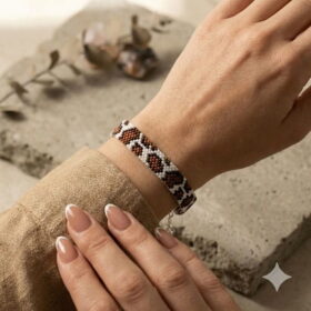 Detailed macro view of the luxurious gold-and-black palette and geometric patterns of the cow print bracelet on a textured stone slab.