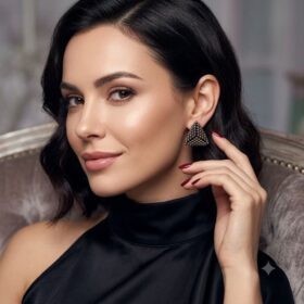 Model wearing brown 3D beaded geometric triangle stud earrings in a gold-toned finish.