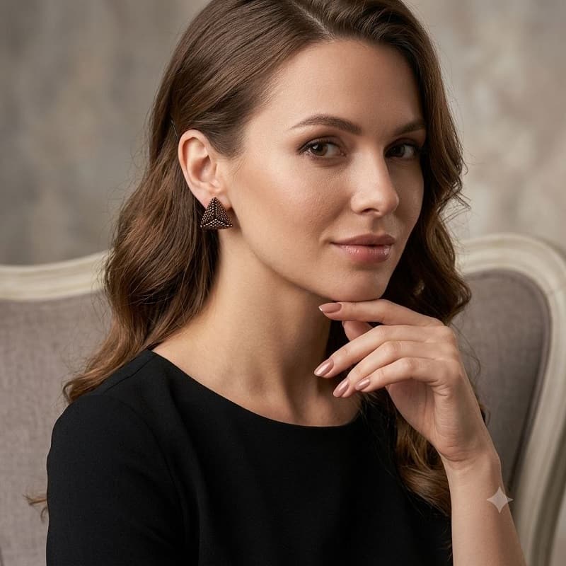 Model posing with luxury handmade gold-toned beaded geometric triangle stud earring.