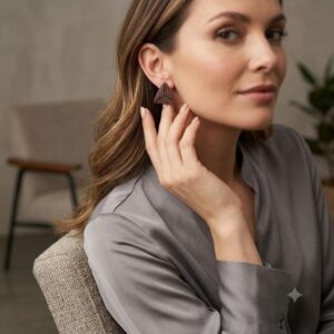 Woman in grey silk blouse wearing handcrafted gold-toned geometric 3D triangle earrings