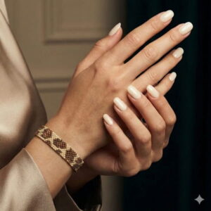 Artisan hand-woven geometric cuff bracelet with metallic gold-finish seed beads shown on a model's wrist.