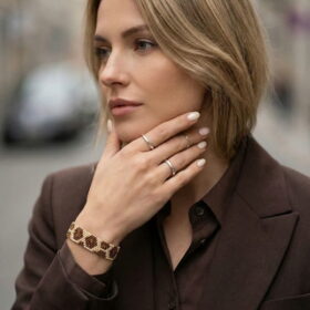 Model wearing a luxury brown geometric seed bead statement bracelet with a dark brown tailored blazer.