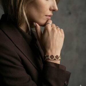 Side view of a sophisticated gold-and-black palette geometric beaded bracelet paired with an elegant brown suit.
