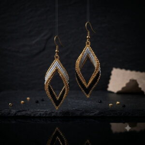 Pair of gold-toned and black open diamond beaded earrings suspended against dark background with reflection.