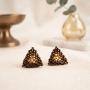 Handmade gold-toned and black beaded pyramid earrings on a white surface.