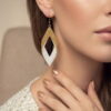 Woman wearing 3D gold-toned and white diamond-shaped beaded earring close up.
