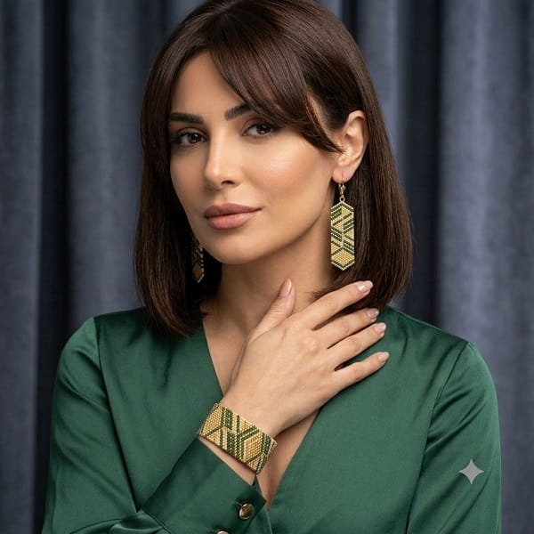 Model in emerald silk blouse wearing golden green beaded artisan jewelry set.