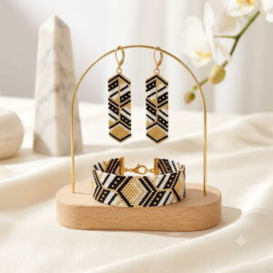 Handmade geometric beaded dangle earrings and cuff bracelet with gold-toned details on wooden display stand.