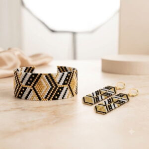 Flatlay view of handcrafted gold-toned geometric bead cuff bracelet and drop earrings.