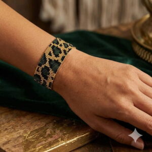 Overhead perspective of a hand showcasing the intricate gold-and-black palette of a luxury beaded bracelet.