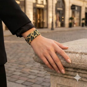 Styled outdoor view of an elegant green leopard beaded statement bracelet worn with a tailored black blazer.