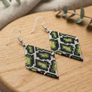 Flat lay photo of two handmade green pattern rhombus earrings on a rustic wooden surface.