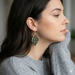 Side profile of a model styling the green geometric pattern artisan beaded earrings with a cozy grey sweater.