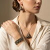 Model wearing the black and gold-toned pyramid jewelry set with a white blouse.