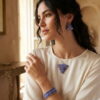 Lifestyle shot of a woman wearing the artisanal royal blue woven bead jewelry set with a classic silk blouse.