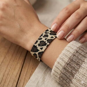 A close-up view of the flexible texture and comfortable fit of the hand-woven leopard statement cuff on a woman's wrist.
