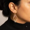 Side profile of a model wearing a handmade mauve and gold-toned 3D beaded diamond drop earring.