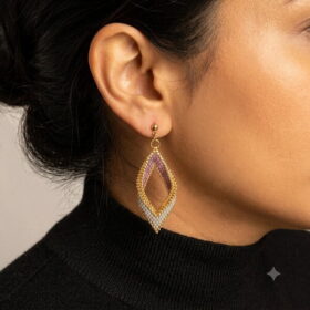 Side profile of a model wearing a handmade mauve and gold-toned 3D beaded diamond drop earring.