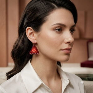 Model in white button-up silk shirt wearing red beaded triangle dangle earrings.