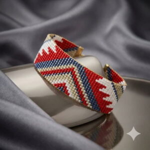 Luxury artisan beaded cuff bracelet featuring a red geometric pattern displayed on a rustic wooden tabletop