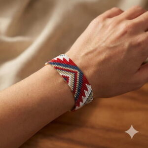 Close-up view of a woman's wrist wearing a luxury hand-woven red geometric beaded cuff bracelet.