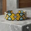 Artisan geometric cuff bracelet featuring a luxurious gold-and-black palette with vibrant blue and yellow beads.