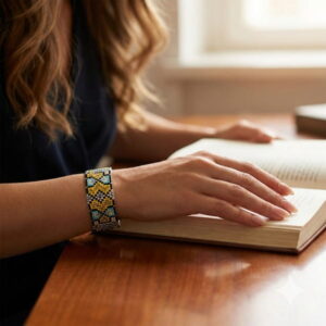Close-up of a structured geometric seed bead bracelet worn while reading a book.
